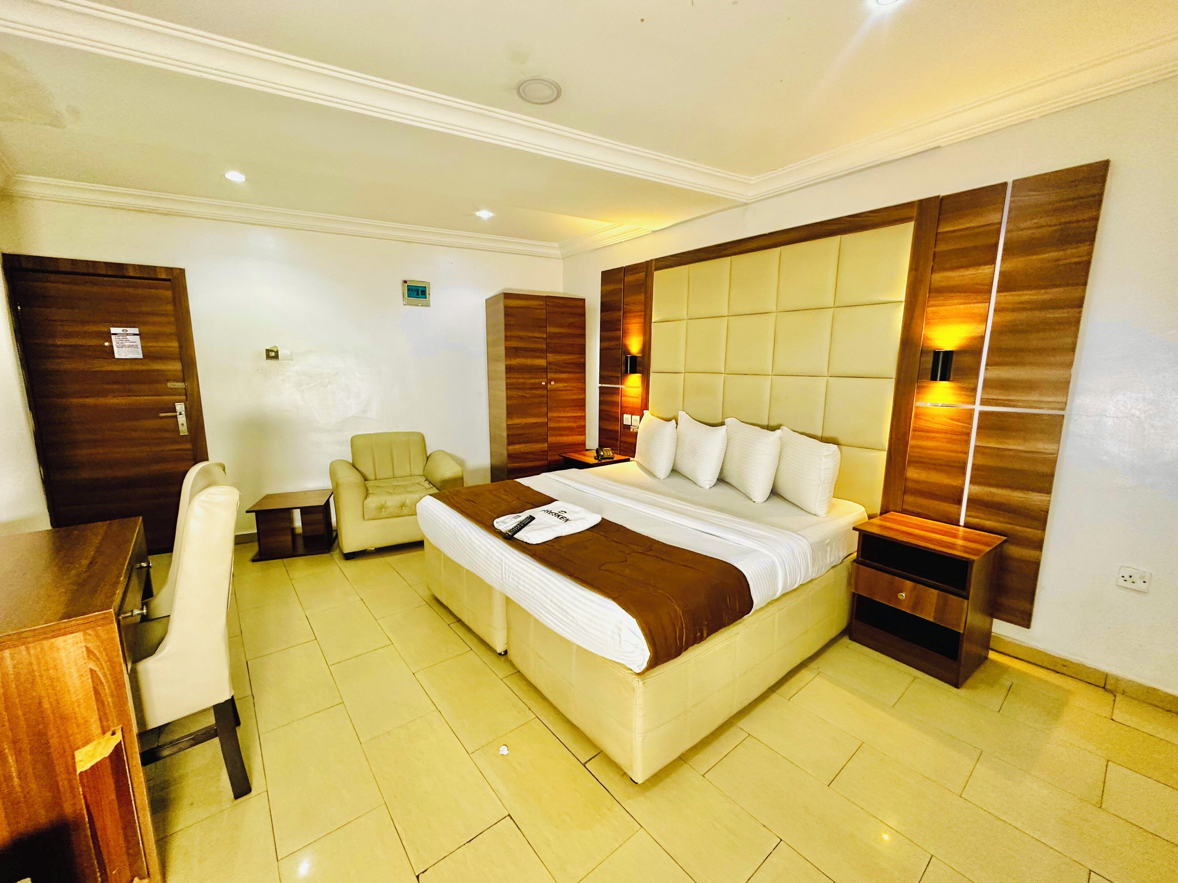 A hotel room with a bed, bedside tables, a desk, and a chair.