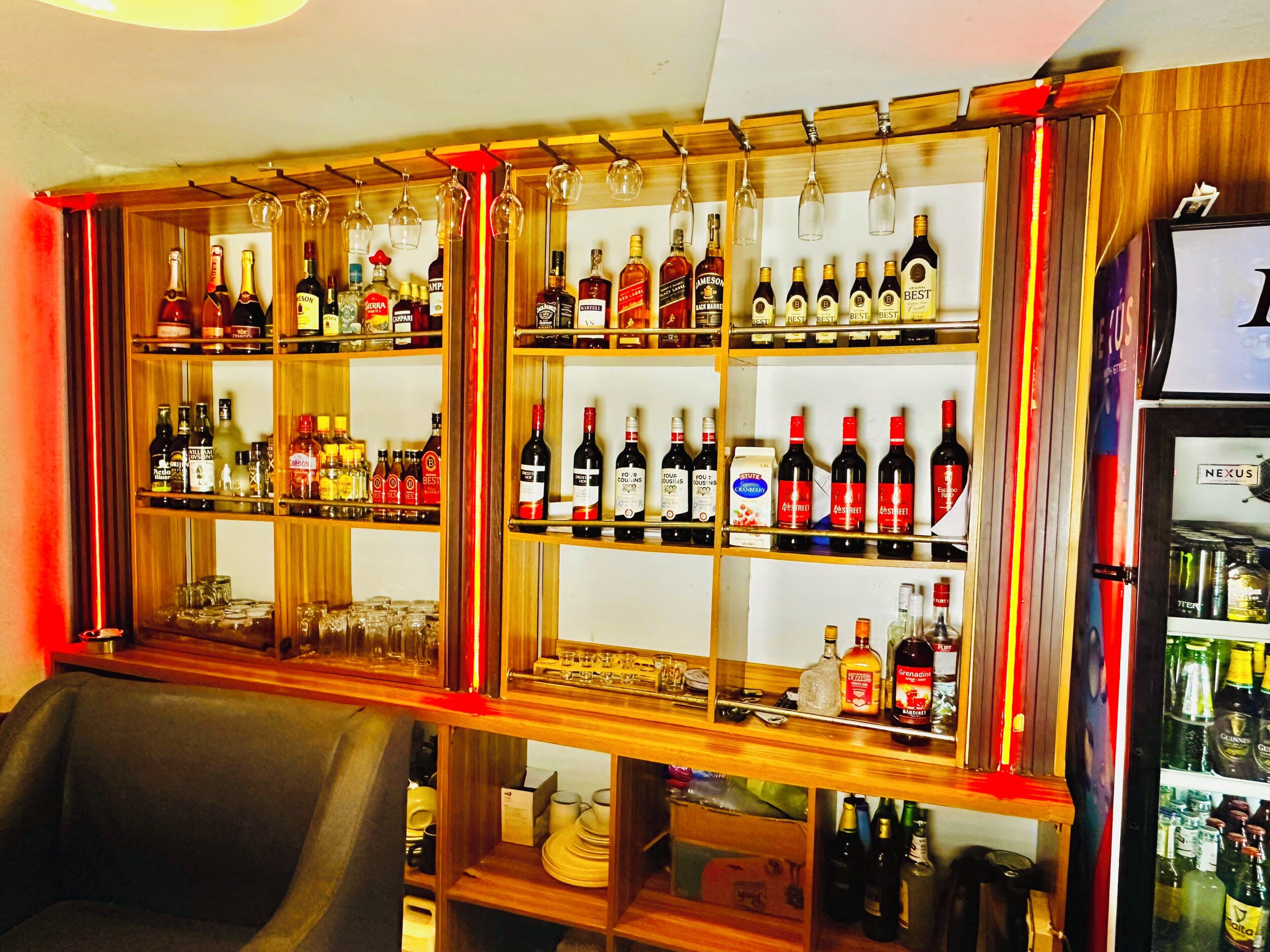 A bar area with shelves stocked with various liquor bottles and glasses.