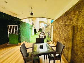 A narrow indoor space with a dining table and chairs, a green wall, and a textured wall on one side. - PRESKEN HOTEL ALADE (Lagos)