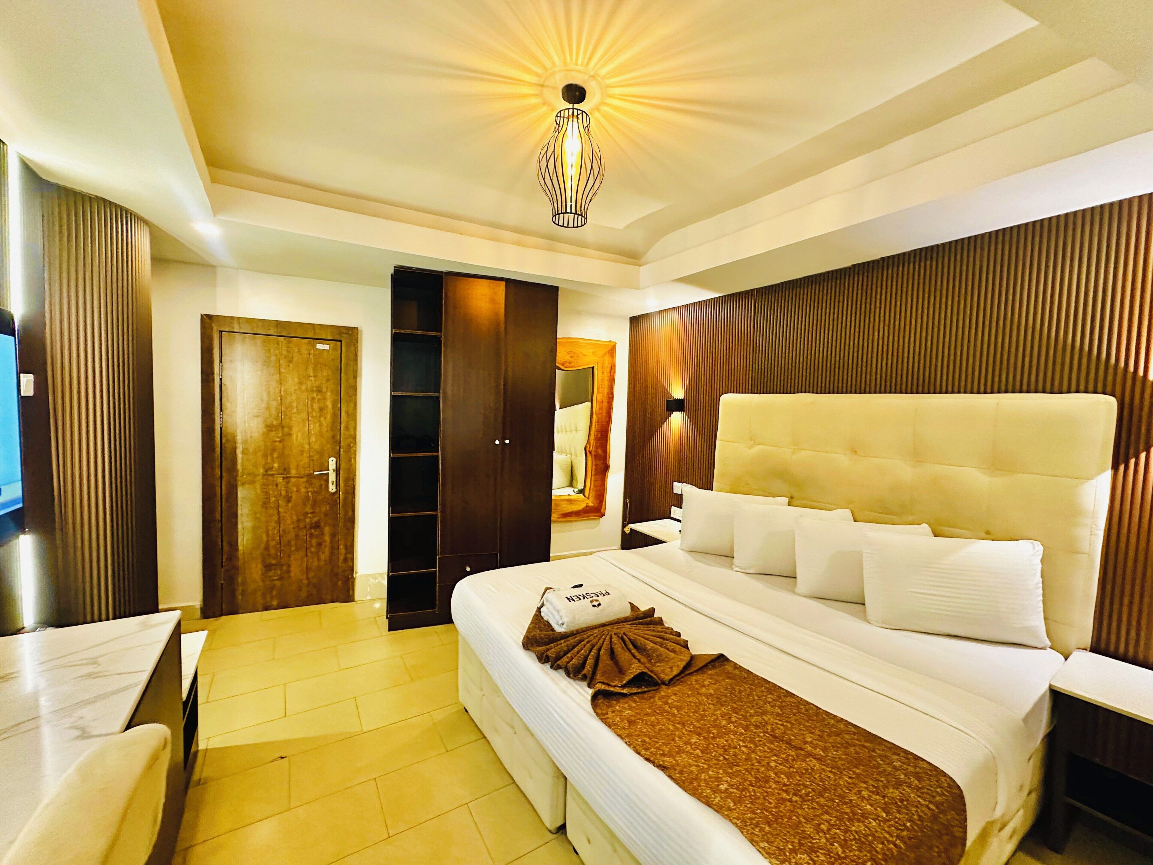 A hotel room with a large bed, a wardrobe, a desk, and a mirror.