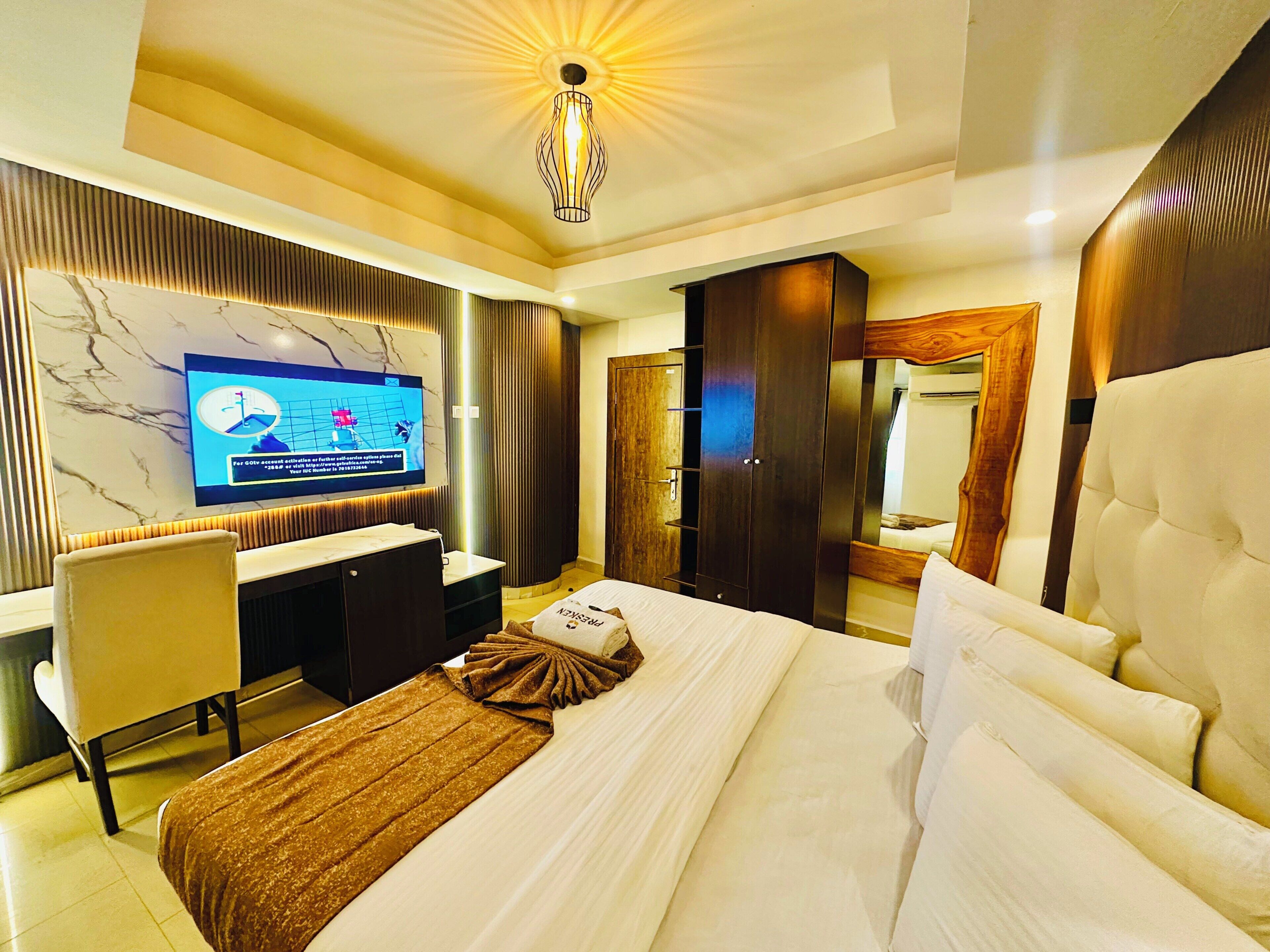Una habitación de hotel con cama, escritorio, televisor y armario.