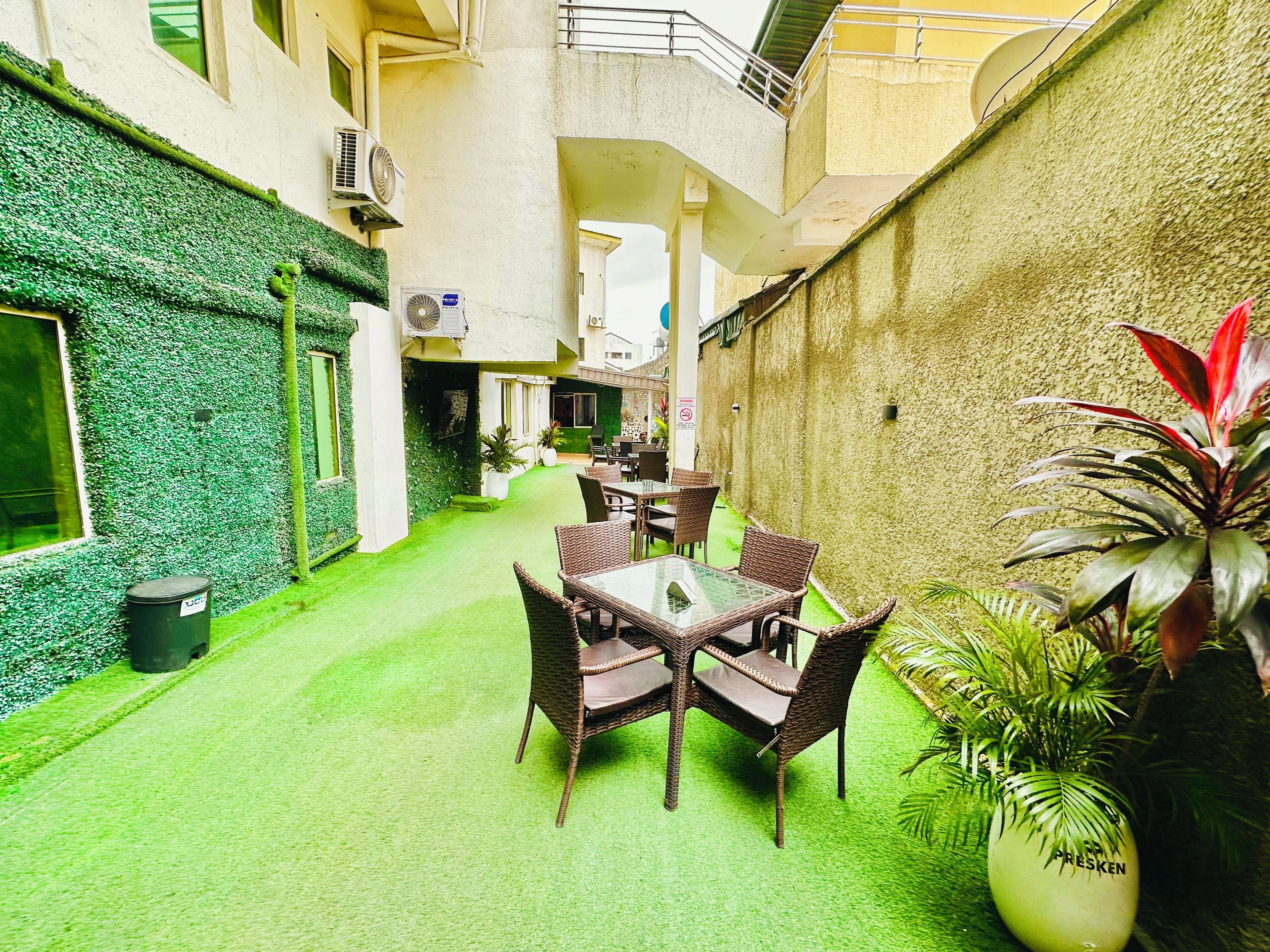 A courtyard with a dining area, green walls, and potted plants.