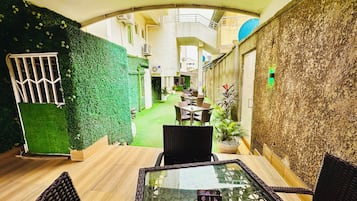 An indoor dining area with a glass table, wicker chairs, and a green wall.