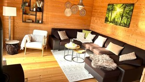 A cozy living room with a wooden interior, a sofa set, a coffee table, a side table, and a lamp.