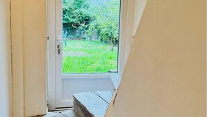 A doorway leading to a garden with a wooden bench and a white door. - Town house 10 min from Futuroscope (Migné-Auxances)