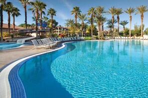 Ein Pool mit Liegestühlen und Palmen.