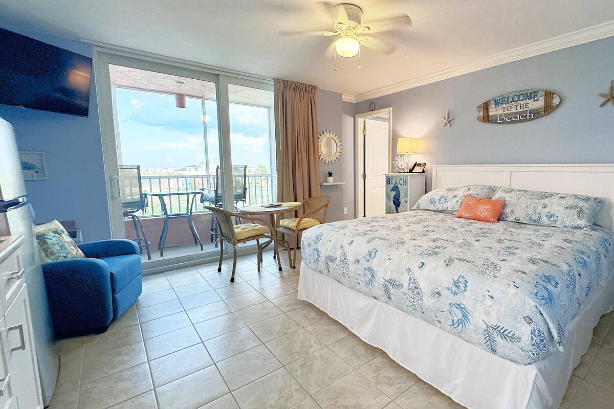 Une chambre avec un lit, une chaise, une table et un balcon offrant une vue.