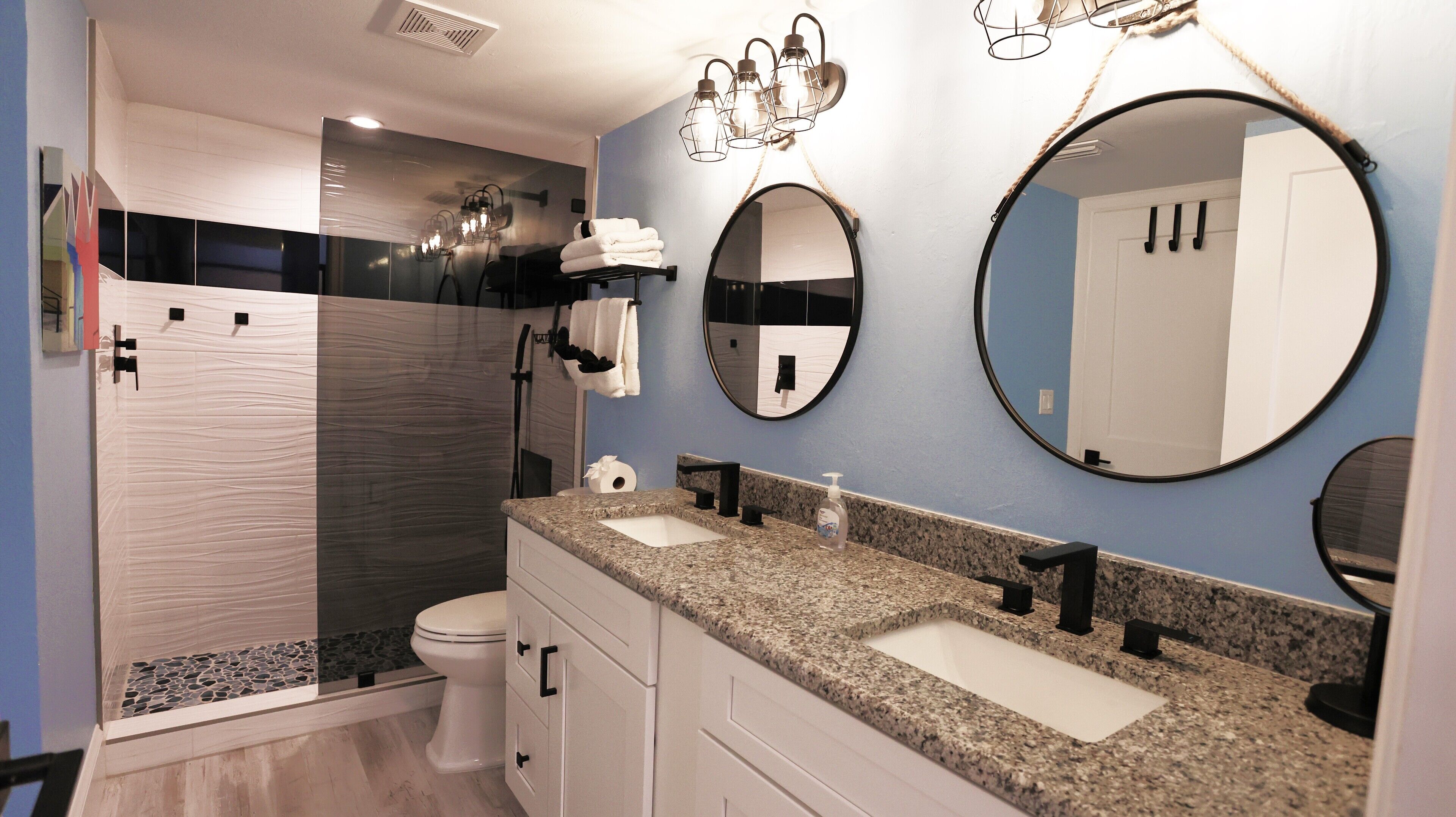 Une salle de bain moderne avec deux lavabos, des toilettes, une douche et un grand miroir.