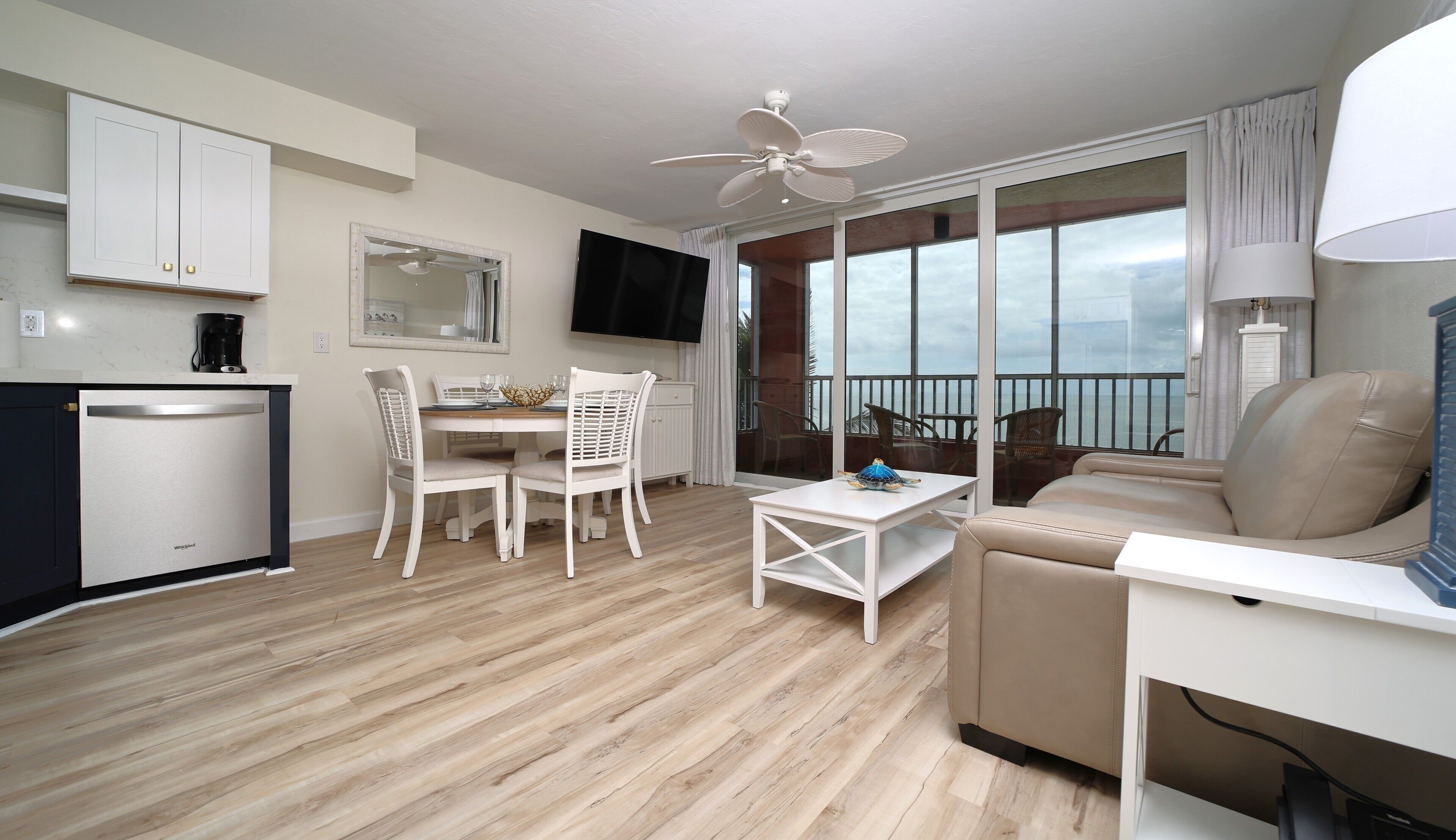 A modern living room with a balcony, a dining area, and a kitchen.
