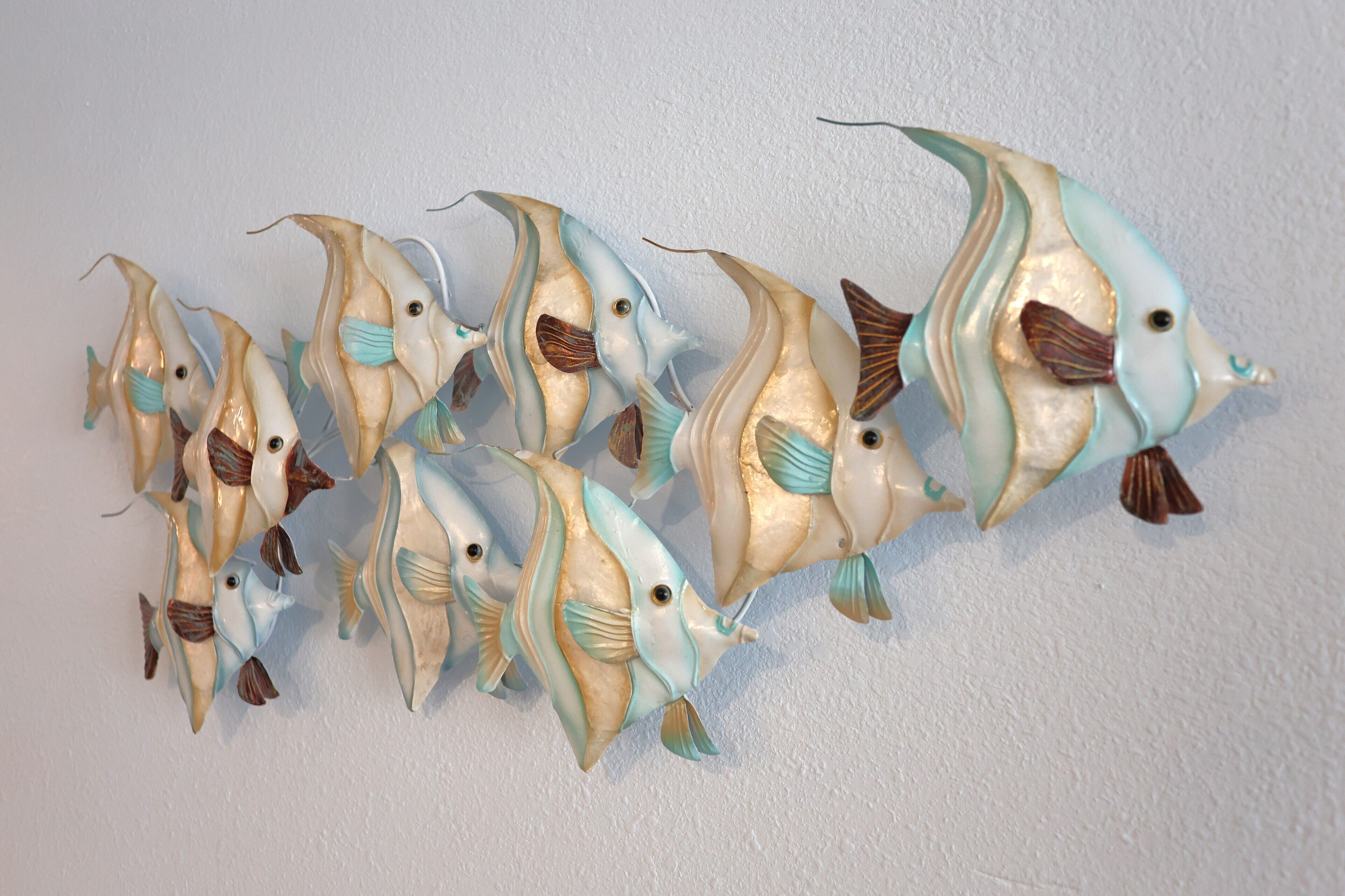 Une sculpture décorative représentant un poisson, conçue pour être fixée au mur.
