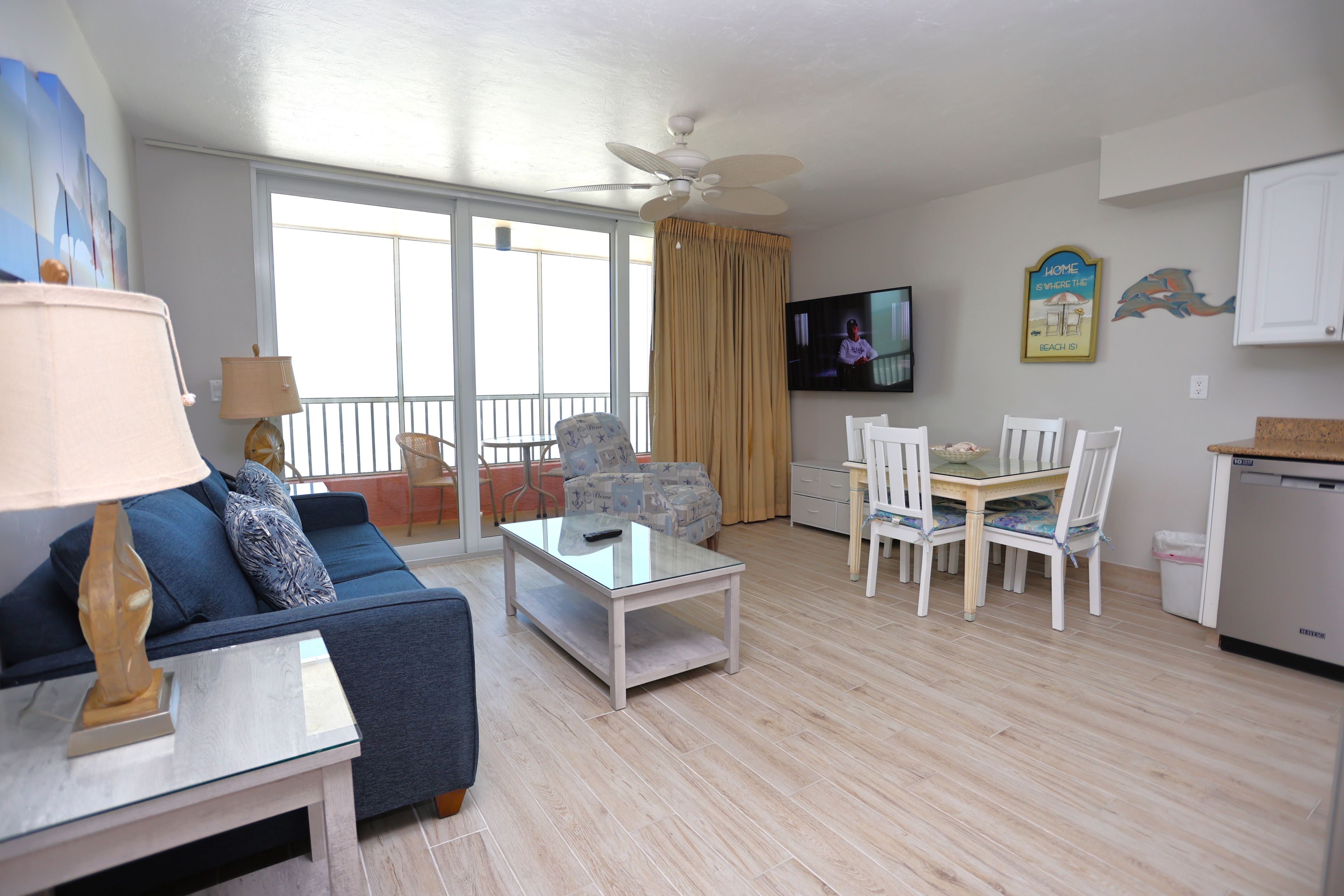 Una sala de estar con un sofá, una mesa de centro, un televisor y una zona de comedor con sillas y una mesa.
