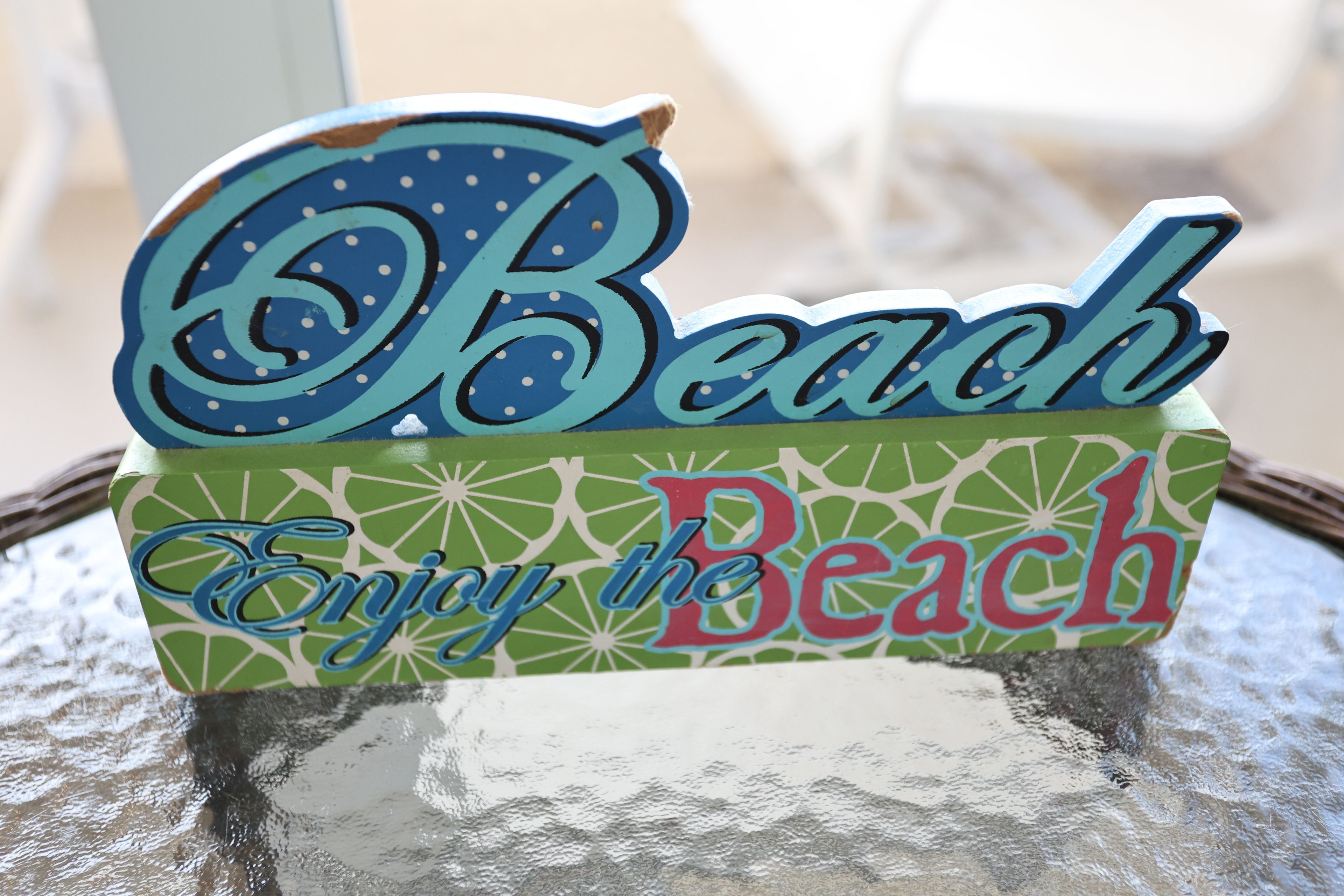 Un panneau décoratif sur lequel figurent les mots « Plage » et « Profitez de la plage », le tout sur une surface texturée.