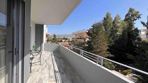 A balcony with a view of a residential area, a table, and chairs.
