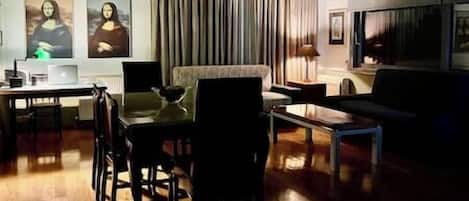 Una sala de estar con comedor, un sofá, una mesa de centro, un televisor y dos cuadros en la pared.