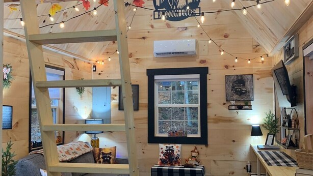 A cozy cabin interior with a loft bed, a desk, and a ladder. - Raccoon Lodge at Coops Creek Cabins (Dunlap)