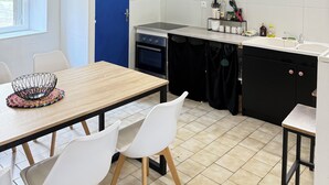 Una cucina compatta con una porta blu, un tavolo da pranzo con sedie e un piccolo piano di lavoro con un lavello.
