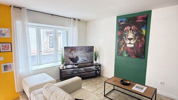 Un soggiorno con divano, tavolino, televisore e opere d'arte alle pareti.