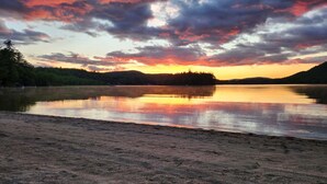 A calm lake with a sandy shore and a forested hill in the background. - Modern Chalet Near Mt. Sunapee & Lake Massasecum (Bradford)