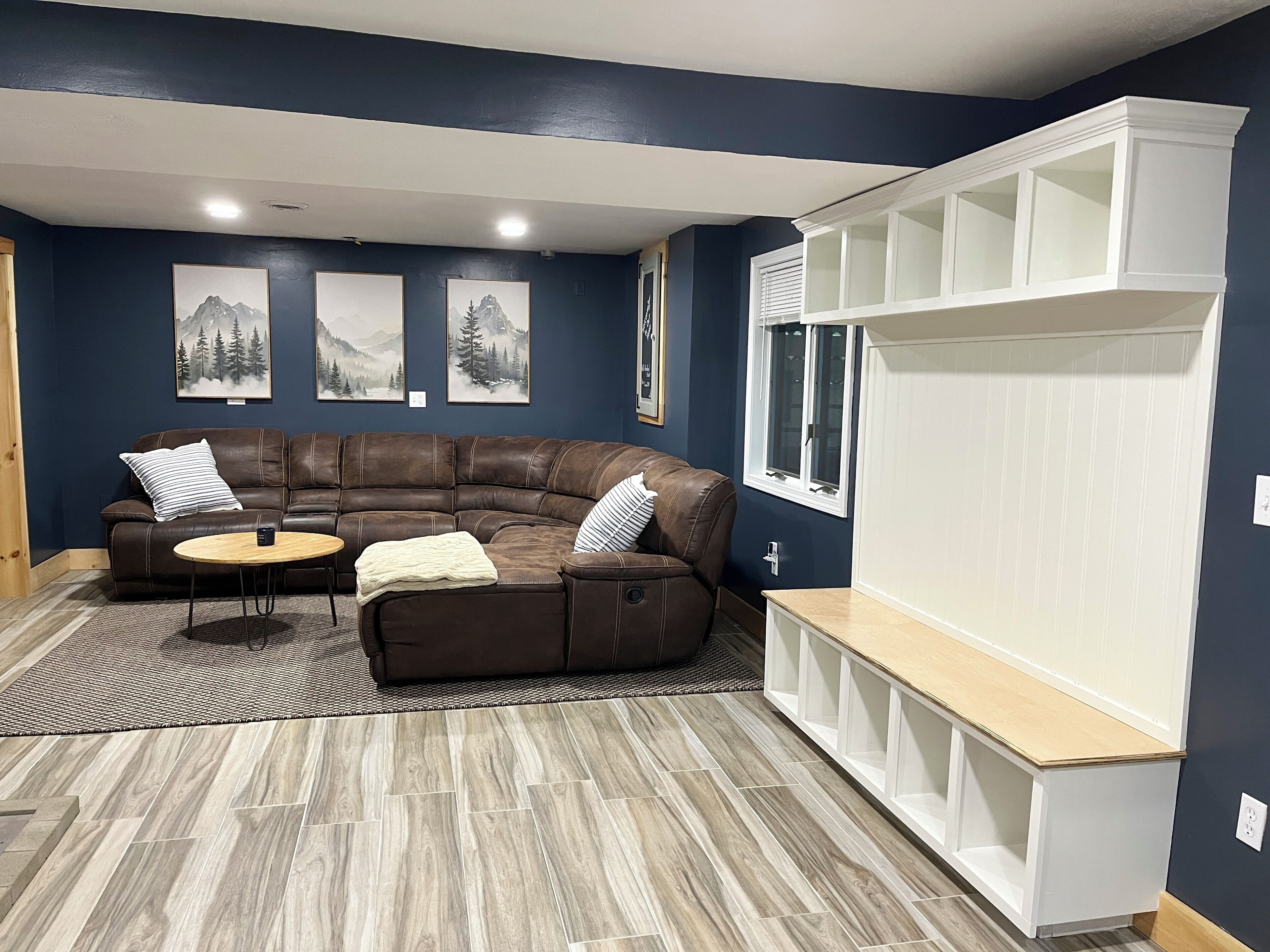 A living room with a sectional sofa, a small round table, and a built-in shelving unit.