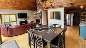 A spacious living area with a fireplace, a television, and a dining table with chairs. - Modern Chalet Near Mt. Sunapee & Lake Massasecum (Bradford)