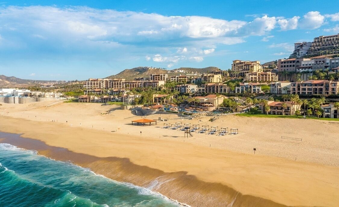 Un resort costero con villas frente a la playa, una playa de arena y vistas al océano.