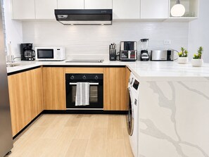 Cocina compacta con microondas, cafetera, tostadora y horno integrado.