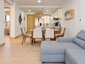 A modern living room with a grey sofa, wooden dining table, and chairs.