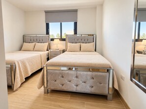 A hotel room with two beds, a large window, and a view of palm trees.
