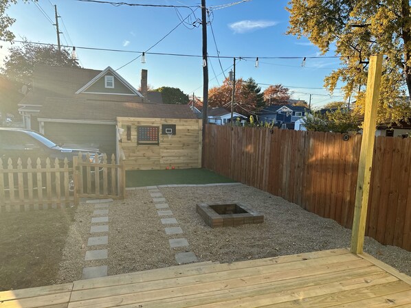 A backyard with a wooden fence, a basketball hoop, a small shed, and a car parked in the driveway. - Like a Local in the Heart of Indy – Cozy Home, Walk to Downtown Attractions! (Indianapolis)
