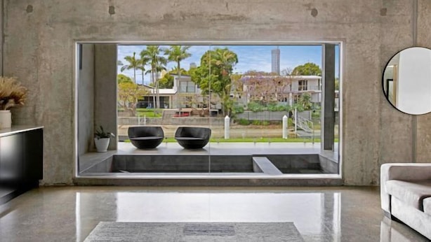 A modern living room with a large window, a flat-screen TV, and a round mirror. - Luxico Urban Hideaway (Pet Friendly) (Broadbeach Waters)