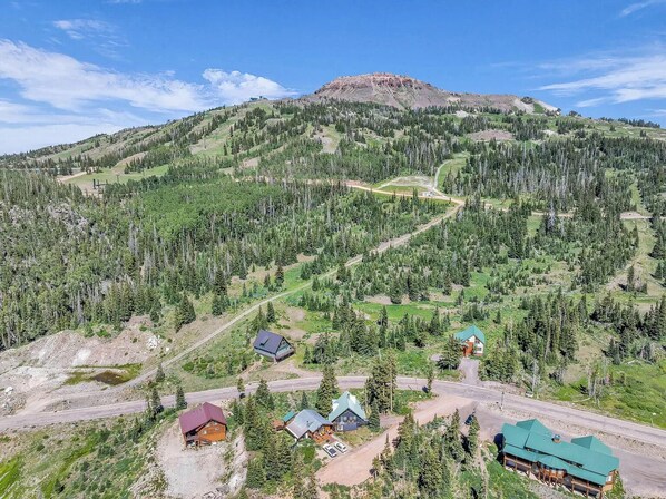 A mountain lodge with multiple cabins, a ski trail, and a prominent mountain peak.