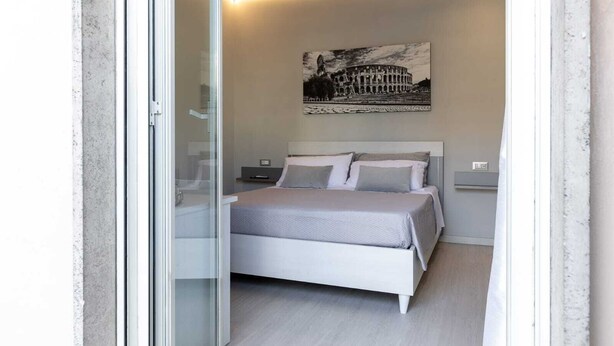 Un dormitorio moderno con cama, mesita de noche y un cuadro colgado en la pared del Coliseo.