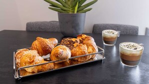 Una mesa con cruasanes, una planta en maceta y dos tazas de café.