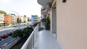 Un balcón con vistas a una calle concurrida y edificios cercanos.