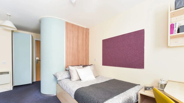 A bedroom with a bed, a desk, a chair, a bookshelf, and a door. - Student Only Gibson Street (Glasgow)