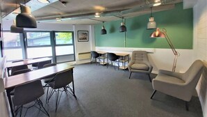 A modern office space with a long table, several chairs, and pendant lighting. - Student Only Gibson Street (Glasgow)