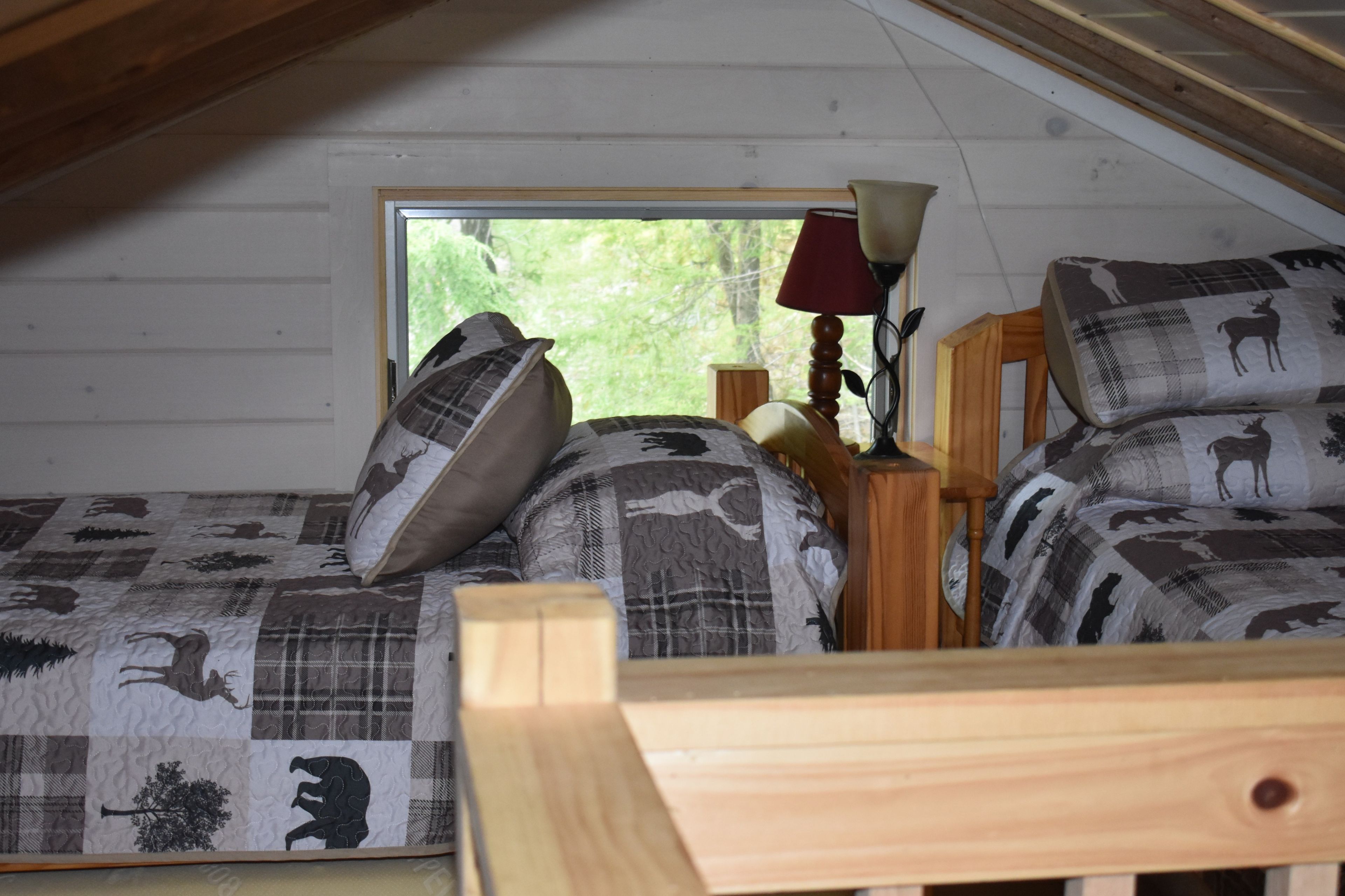 A cozy attic bedroom with two beds, each with a unique animal-themed quilt.