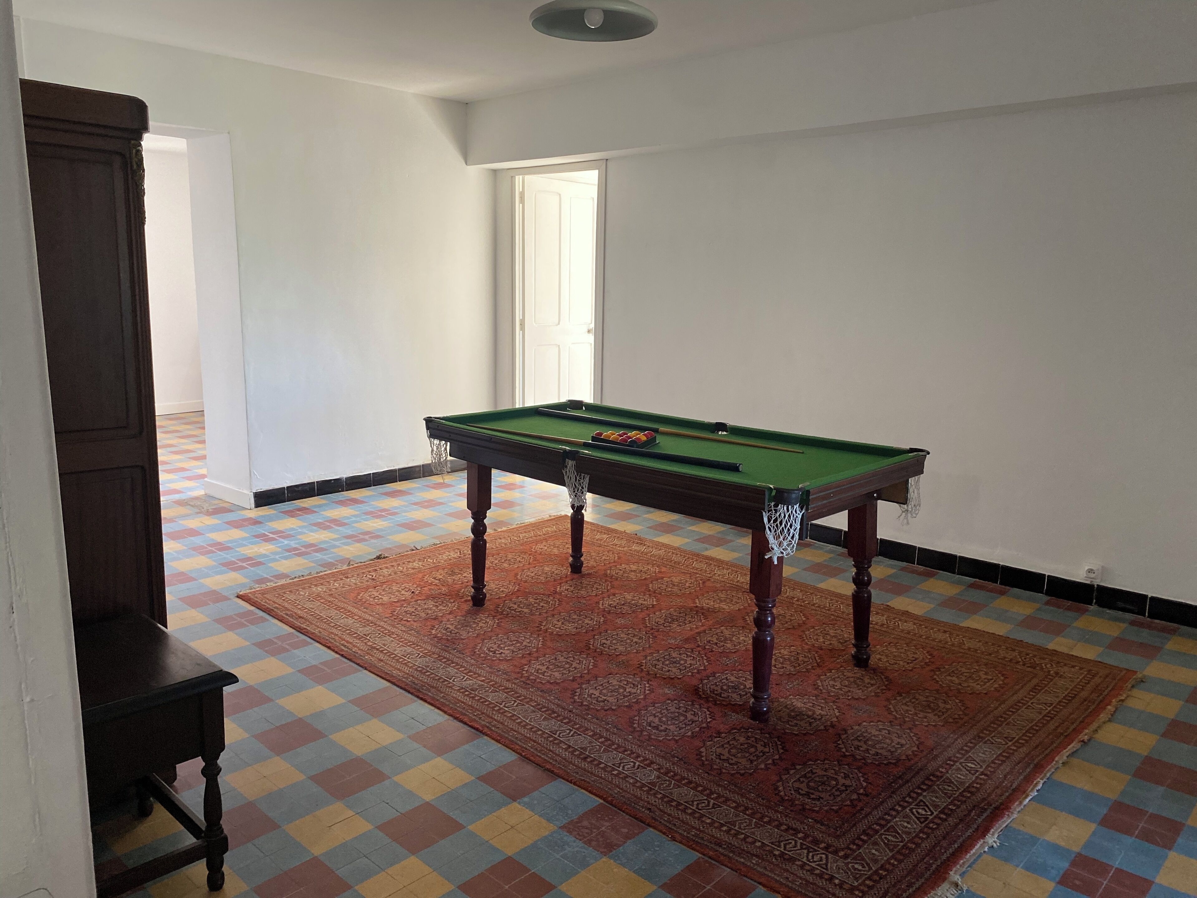 Une pièce avec une table de billard, une moquette à motifs et un sol à carreaux.