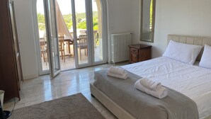 A bedroom with a large bed, a wooden dresser, a mirror, and a sliding glass door leading to an outdoor patio with a table and chairs. - Large house with private swimming pool, enclosed grounds that will enchant your vacations.  (Saint-Ambroix)