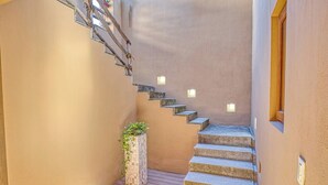 A narrow staircase with stone steps and wall-mounted lights, leading to a wooden deck area. - Casa Piedra: 4BR/4BA, Private Pool & Rooftop Palapa, Sleeps 8 San Pancho Nayarit (San Francisco)