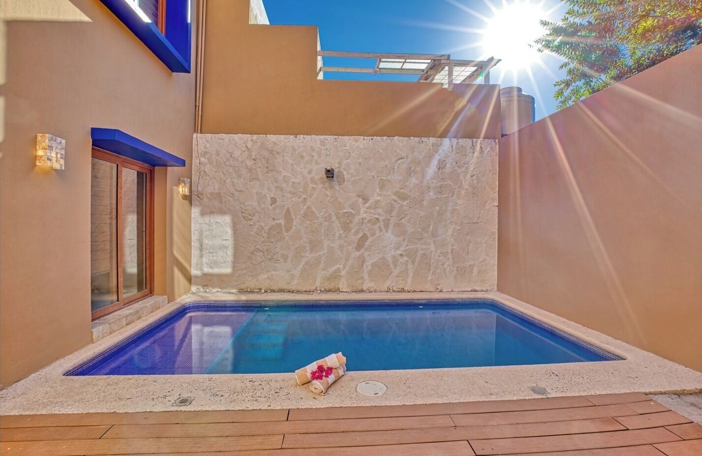An outdoor swimming pool with a stone wall and wooden deck.