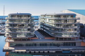 A modern multi-story hotel with a glass facade, located near a marina with boats. - Waterfront Vibes by Wonderful Italy (Genoa)
