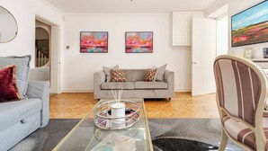 Una sala de estar moderna con un sofá gris, una mesa de centro redonda y un televisor en la pared.
