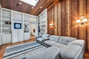 Un soggiorno moderno con un divano componibile, scaffali a incasso e una parete decorata in legno.