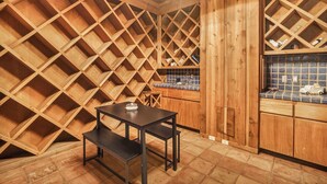 A wooden interior with a table and bench, a kitchen area with blue tiles, and a wooden ceiling with a crisscross pattern. - Luxury Austin Estate – Tranquil, Spacious & Packed with Games and Pool. (Austin)