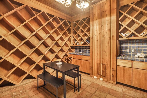 A wooden interior with a table and bench, a kitchen area with blue tiles, and a wooden ceiling with a crisscross pattern. - Luxury Austin Estate – Tranquil, Spacious & Packed with Games and Pool. (Austin)
