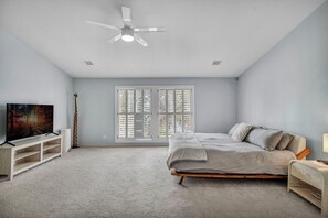 A bedroom with a bed, a TV, a ceiling fan, and a window with blinds. - Luxury Austin Estate – Tranquil, Spacious & Packed with Games and Pool. (Austin)