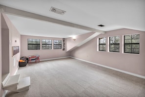 A spacious attic room with high ceilings, large windows, and a sloped roof.