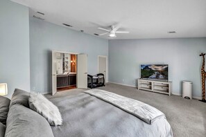 Quarto com cama, ventilador de teto, televisão e uma estátua de girafa.