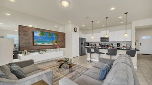 Una cocina moderna con armarios blancos, un refrigerador de acero inoxidable y una isla central con taburetes de bar.